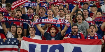 Diverse US soccer supporters cheering with banners in a vibrant stadium.