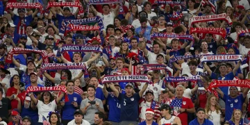 Passionate US soccer fans cheering in a stadium, showcasing vibrant fan culture